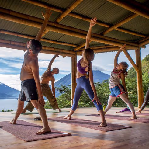 People sitting in meditation on a yoga platform over the lake in early morning light